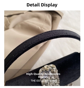 Detailed close-up of velvet texture and sparkling rhinestone buckle on black evening bag