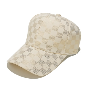 Close-up of a cream-colored baseball cap featuring a metallic gold checkerboard pattern