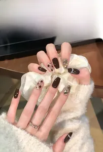 Detail of dark brown press-on nails with leopard print and sparkling rhinestones