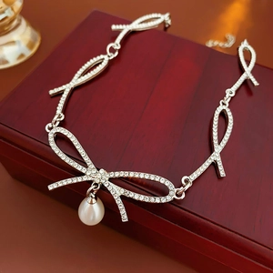 Détail du collier noeud argenté avec diamants étincelants et perle en forme de goutte