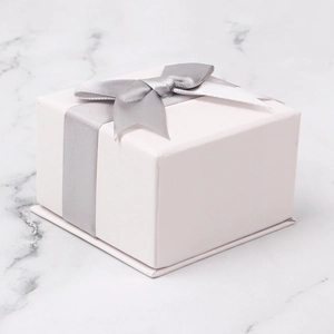 Elegant white jewelry gift box with grey satin bow on a marble surface background