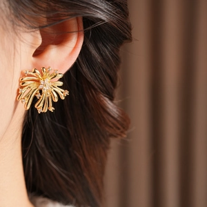 Détail macro d'une boucle d'oreille feu d'artifice dorée avec zircons portés
