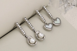 Detailed view of silver earrings featuring pearls, rhinestones and heart-shaped shell
