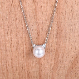 Detail of silver cat ear pendant with pearl and tiny cubic zirconia on wood background