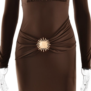 Détail de robe élégante marron foncé avec boucle dorée en forme de soleil et tissu drapé