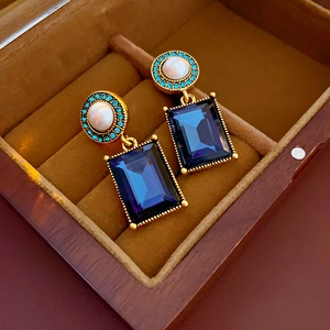 Detailed macro view of vintage square blue gemstone earrings with white pearl accents