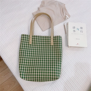 Détail du sac cabas à carreaux verts avec poignées en cuir marron sur fond blanc piqué