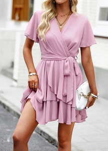 Détail d'une robe courte rose trapèze avec col en V, ceinture nouée et ourlet volanté