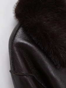 Detail of dark brown leather jacket showing premium grain texture and plush faux fur collar