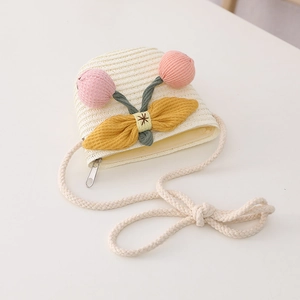 Detail of cream straw crossbody bag for kids with pink flower and yellow bow accents