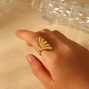 Gold ginkgo leaf open ring in stainless steel worn by model on a warm background