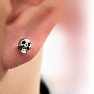 Close-up of vintage silver skull earring showing rustic finish and hip-hop design details
