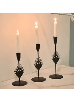 Detail of matte black peacock feather metal candle holders with white spiral candles
