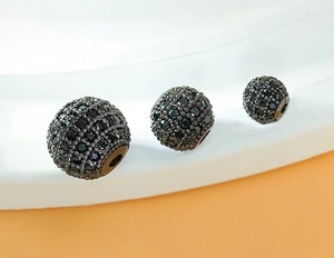 Macro shot of three black pavé-set cubic zirconia round beads for DIY jewelry making