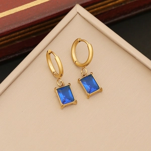 Elegant gold hoop earrings with square blue gemstone pendants on a jewelry display