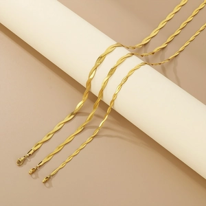 Detailed view of three golden twisted rope and snake chain necklaces on a white stand