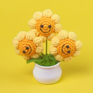 Handmade crochet sunflower potted plant with three yellow smiley faces in a white pot