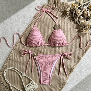 Close-up of pink bikini with wavy texture, metal flower accents and pearl details