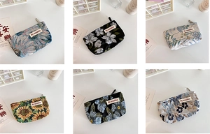 Detail view of six assorted floral embroidered cosmetic bags with zipper closure