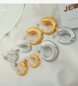 Detail view of gold and silver C-shaped hollow hoop earrings in assorted sizes on white fabric
