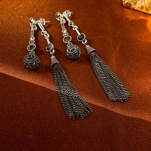 Detailed shot of vintage silver earrings with dark metal spheres and long chain tassels
