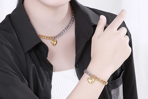Detail of two-tone gold and silver heart pendant necklace and bracelet set on model