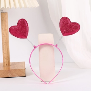 Detail of rose pink heart headband with metal springs and glitter finish on a soft background