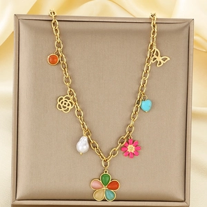 Detail of golden stainless steel necklace with butterfly, heart, and enamel flower charms