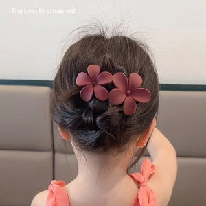 Detail of a young girl wearing two wine red flower-shaped hair clips in a stylish hairstyle
