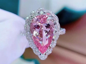 Macro shot of 7.5ct pear-cut pink gemstone ring with diamond halo and pavé setting