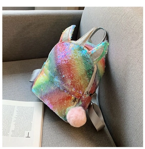 Close-up of rainbow sequin unicorn backpack with gold horn and pink pompom on a sofa