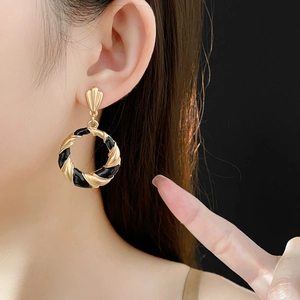 Close-up of black and gold vintage twisted geometric earrings on a model