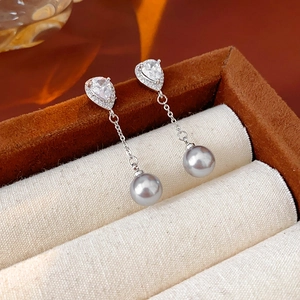 Detail of silver teardrop diamond earrings with grey pearls on jewelry box