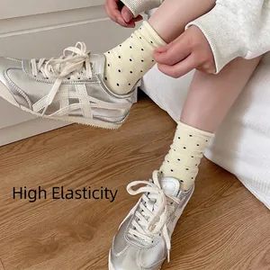 Polka dot crew socks for women in light yellow with elastic ruffled cuffs on model