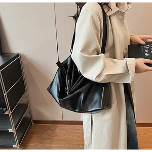 Détail du grand sac cabas en cuir souple noir avec texture brillante porté à l'épaule