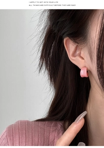 Close-up of pink C-shaped resin stud earring worn by model for a minimalist summer look