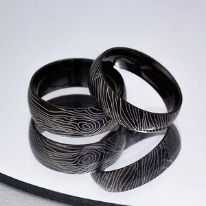 Detail of 6mm and 8mm Damascus steel rings with laser-engraved wood grain texture
