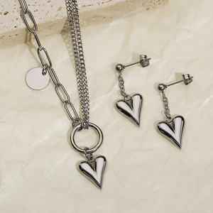 Detail view of silver titanium steel necklace and heart earrings set on stone