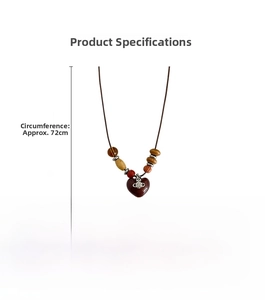Detailed view of heart pendant with saturn ring logo on long wooden bead necklace