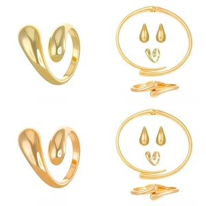 Detail view of 14K gold minimalist jewelry set including collar, bracelet, ring, and studs