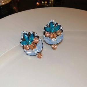 Detail shot of multi-color zircon flower earrings on white porcelain tray