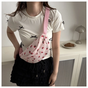 Detail der rosa Cord-Brusttasche mit roten Erdbeer-Stickereien, getragen von einem Modell