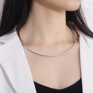 Close-up of minimalist silver metal collar necklace on a model in a white blazer