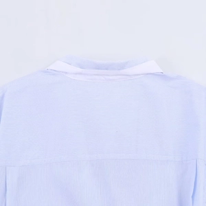 Detail of light blue shirt collar and shoulder seam with clear fabric texture
