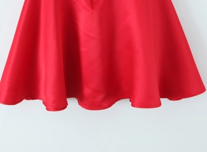 Detailed macro shot of the red satin dress hem with smooth texture and fine stitching