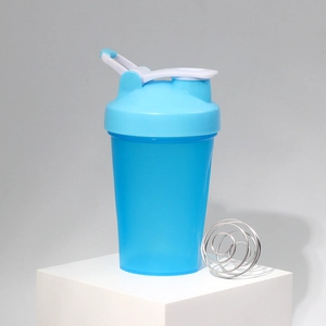Detail of blue protein shaker bottle with measuring scale and metal mixing whisk ball