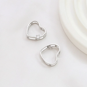 Close-up of silver heart-shaped earring pendants with sparkling zircon stone inlay