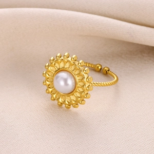 Macro detail of a golden ring featuring a white pearl and starfish-inspired ocean elements