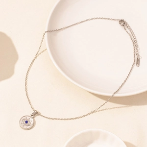 Detail of silver stainless steel evil eye pendant necklace with blue gemstone and zircons