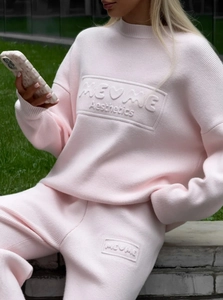 Detail of light pink knitted set featuring embossed ME ME Aesthetics logo on sweater